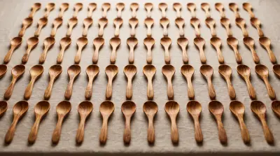 Rows of identical olive wood spoons laid out on linen as a single production batch