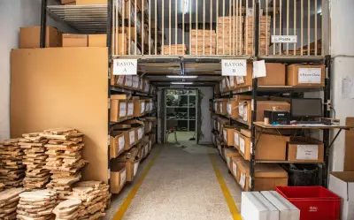 Cartons of packed olive wood orders on labelled racking in the ArtisRaw store, Sfax